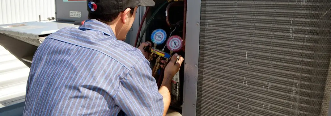 HVAC technician servicing a condenser unit in Elko